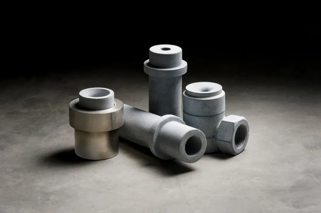 Gray ceramic nozzles, one set in a steel sleeve, on a concrete floor