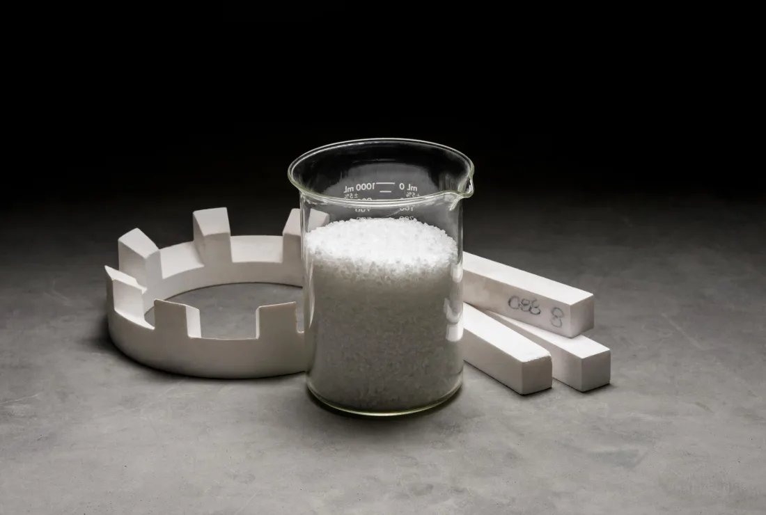 White alumina parts and powder in a glass beaker