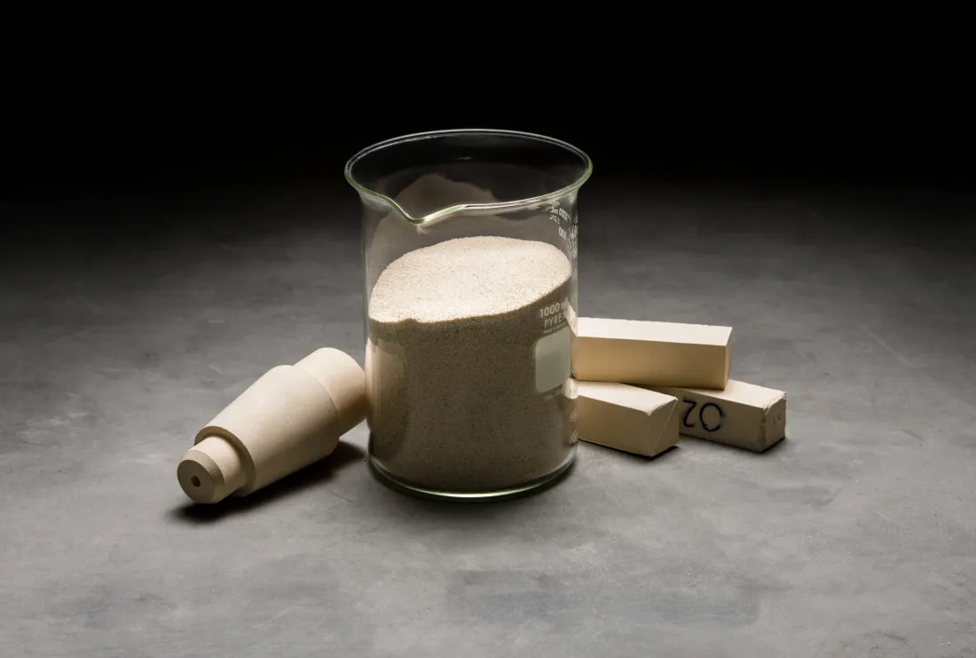 Zirconia shapes next to a beaker of raw material