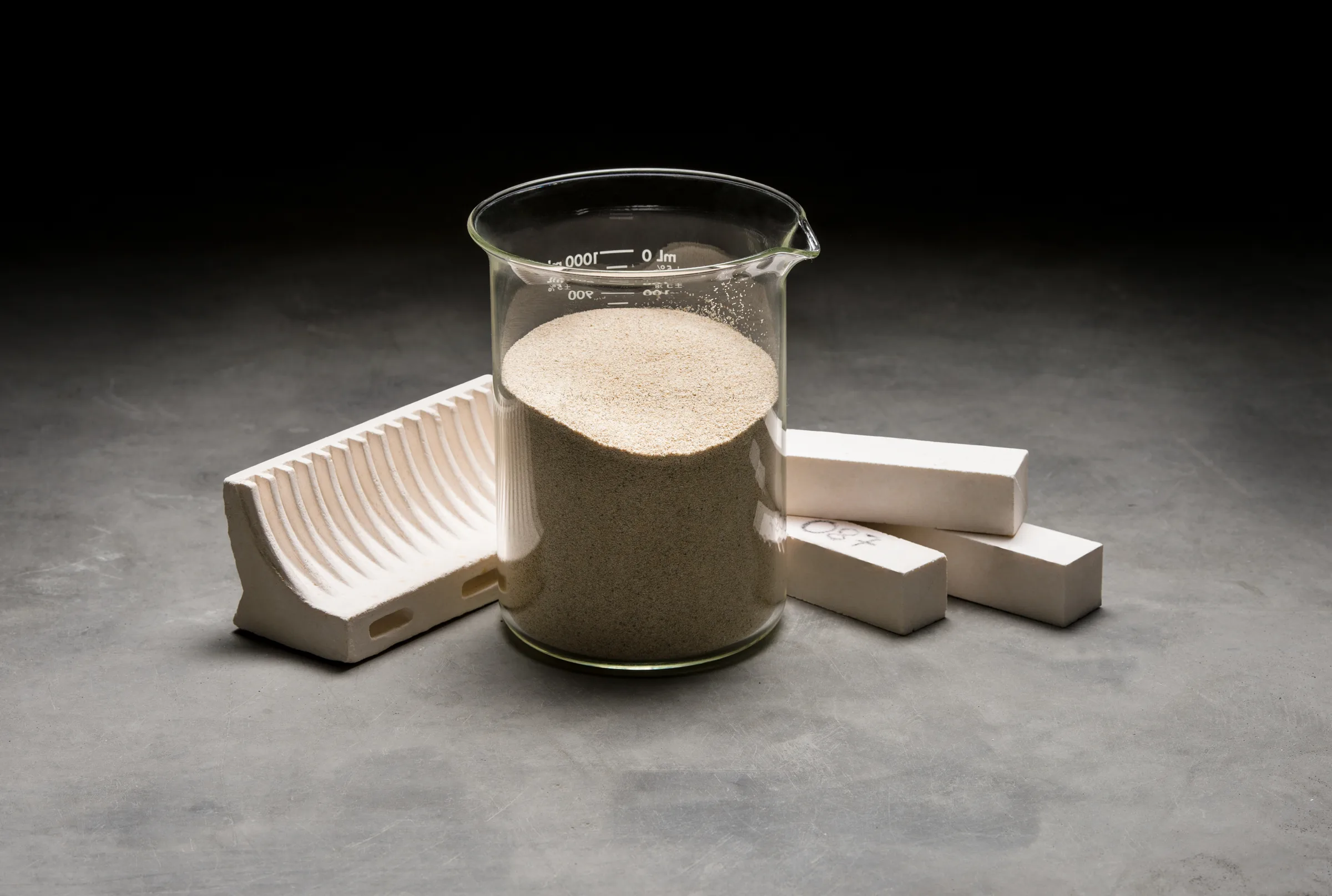 Mullite shapes next to a beaker of raw material