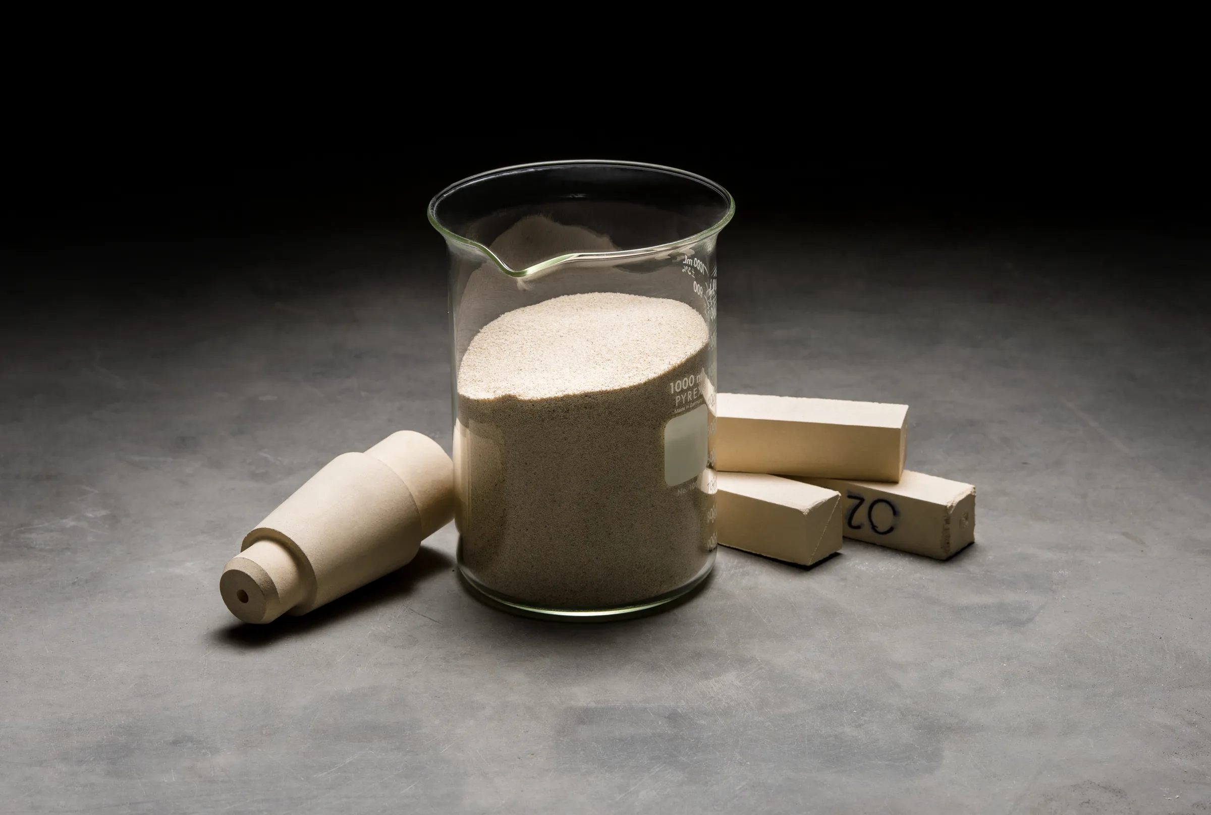 Zirconia shapes next to a beaker of raw material